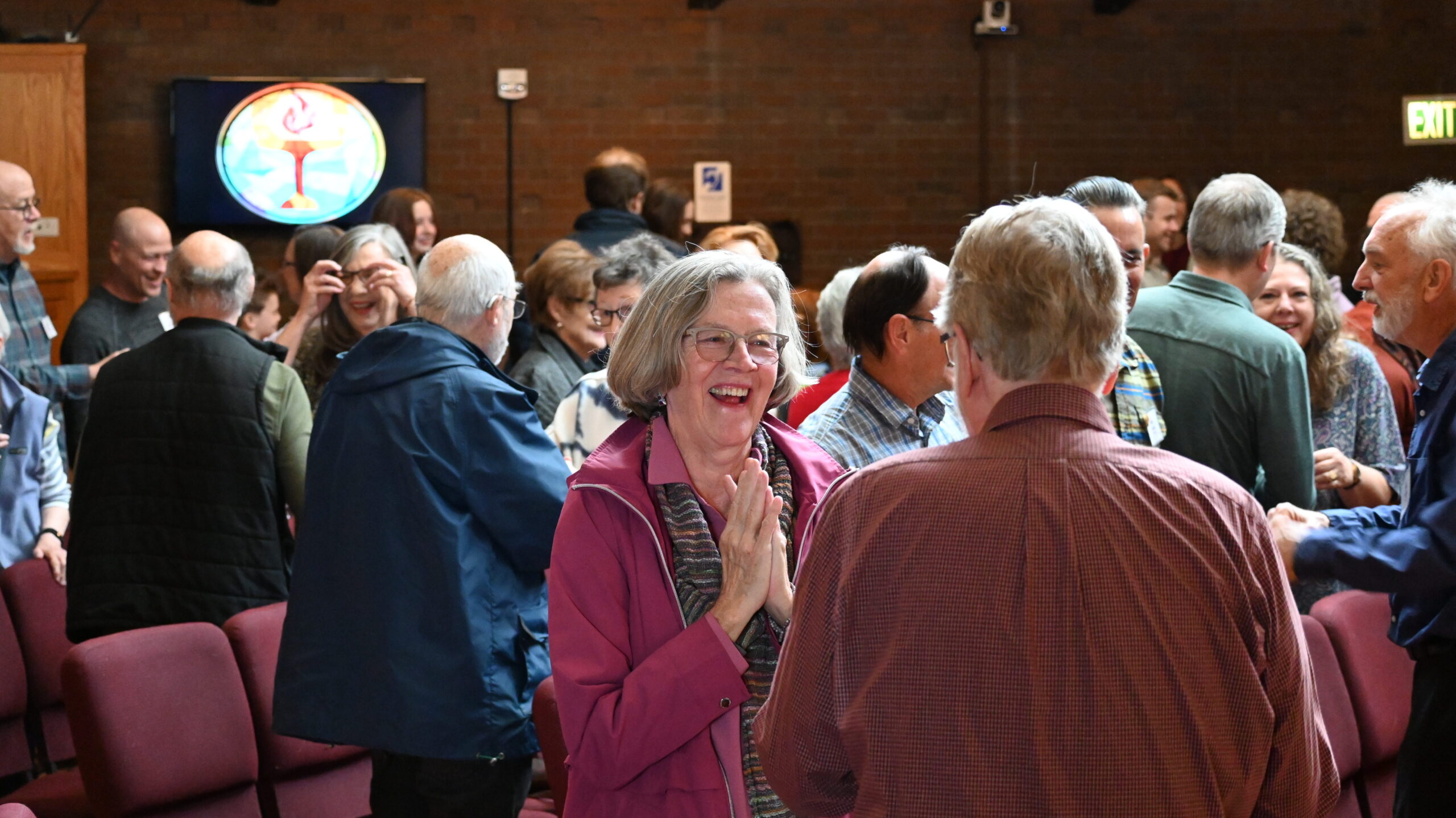 A couple of congregants greet each other during a worship service on a Sunday.